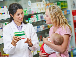 Pharmacist talking to mother with baby in pharmacy