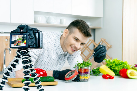A kitchen chef has a video camera set up to film him styling colourful food jpg