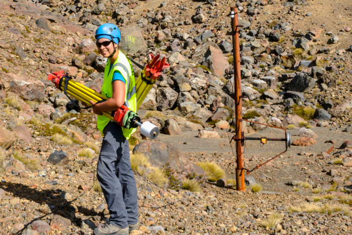 Geophysicist standing on Mt Ruapehu, holding laser-scanning equipment