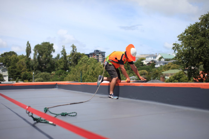 A roofer measuring the edge of a roof 