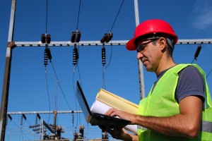 An electrical engineer stands in a power farm and checks things on his lap top
