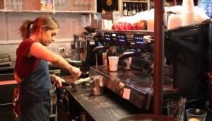 A barista uses a coffee machine to make a coffee.